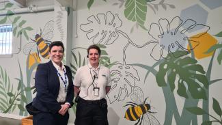 Two staff members standing in front of newly painted wall