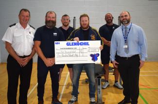 six individuals standing with a cheque
