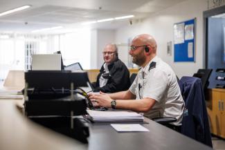 2 prison officers sitting at computers