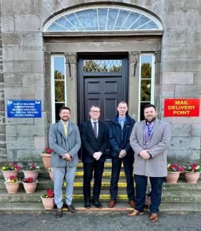 four men standing together infront of building