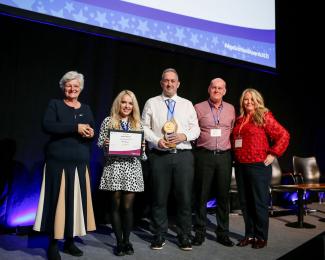 Three staff being presented with an award on stage