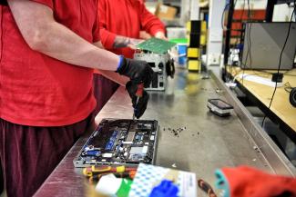 Person fixing computer monitor with screwdriver
