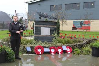 Prison Officer playing bagpipes standing by war memorial